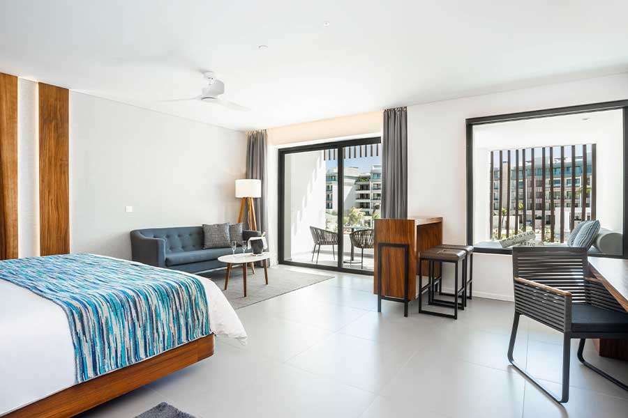 Modern hotel room with balcony and seating area.