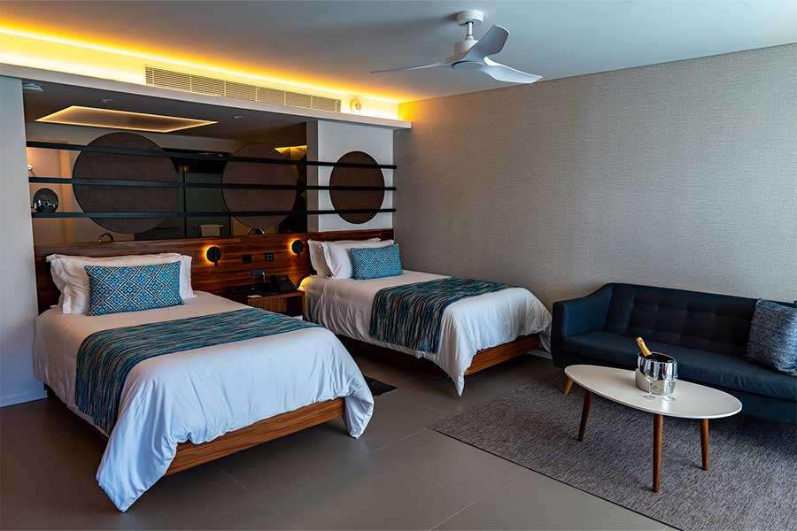 Modern hotel room with two beds and seating area.