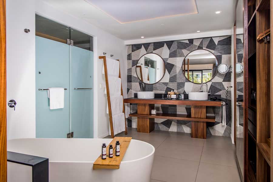 Modern bathroom with bathtub and dual sinks.