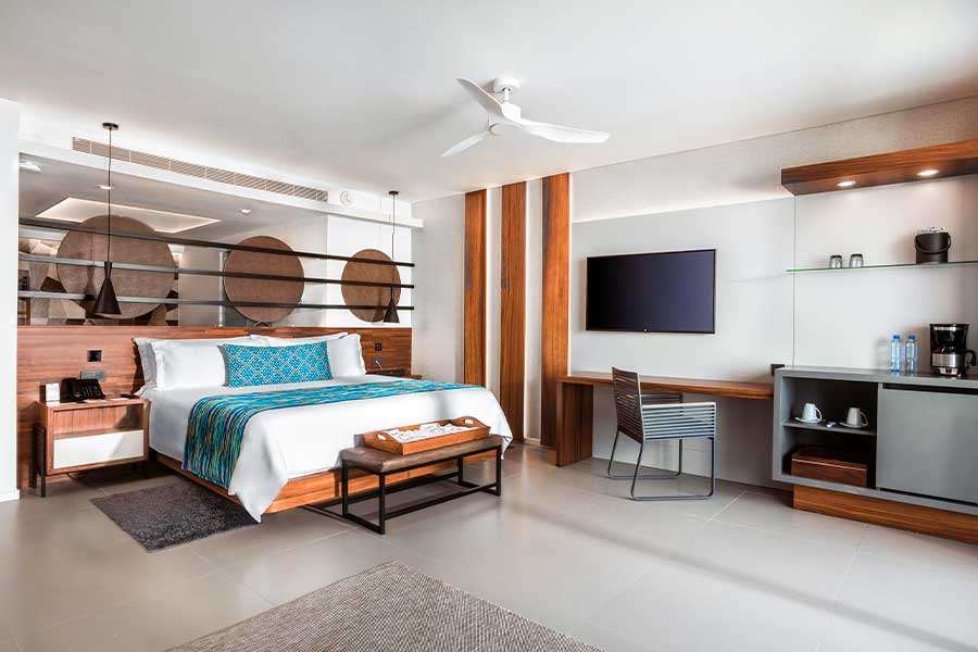 Modern hotel room with bed and workspace.