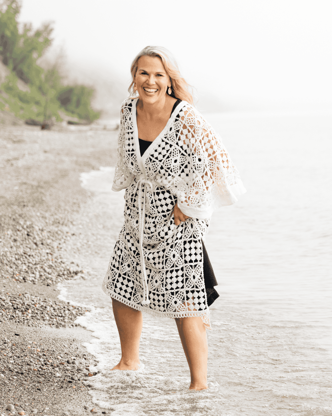 Woman walking along a beach in a crochet dress.
