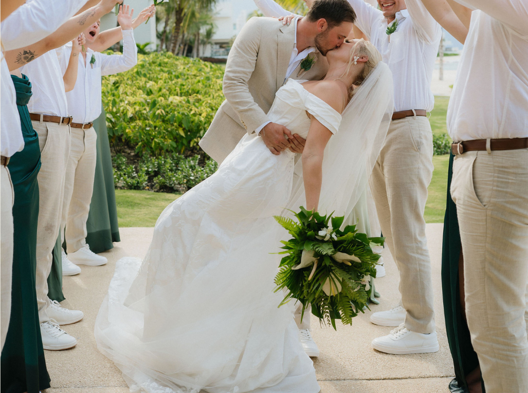 Bride and groom kissing at outdoor wedding ceremony.