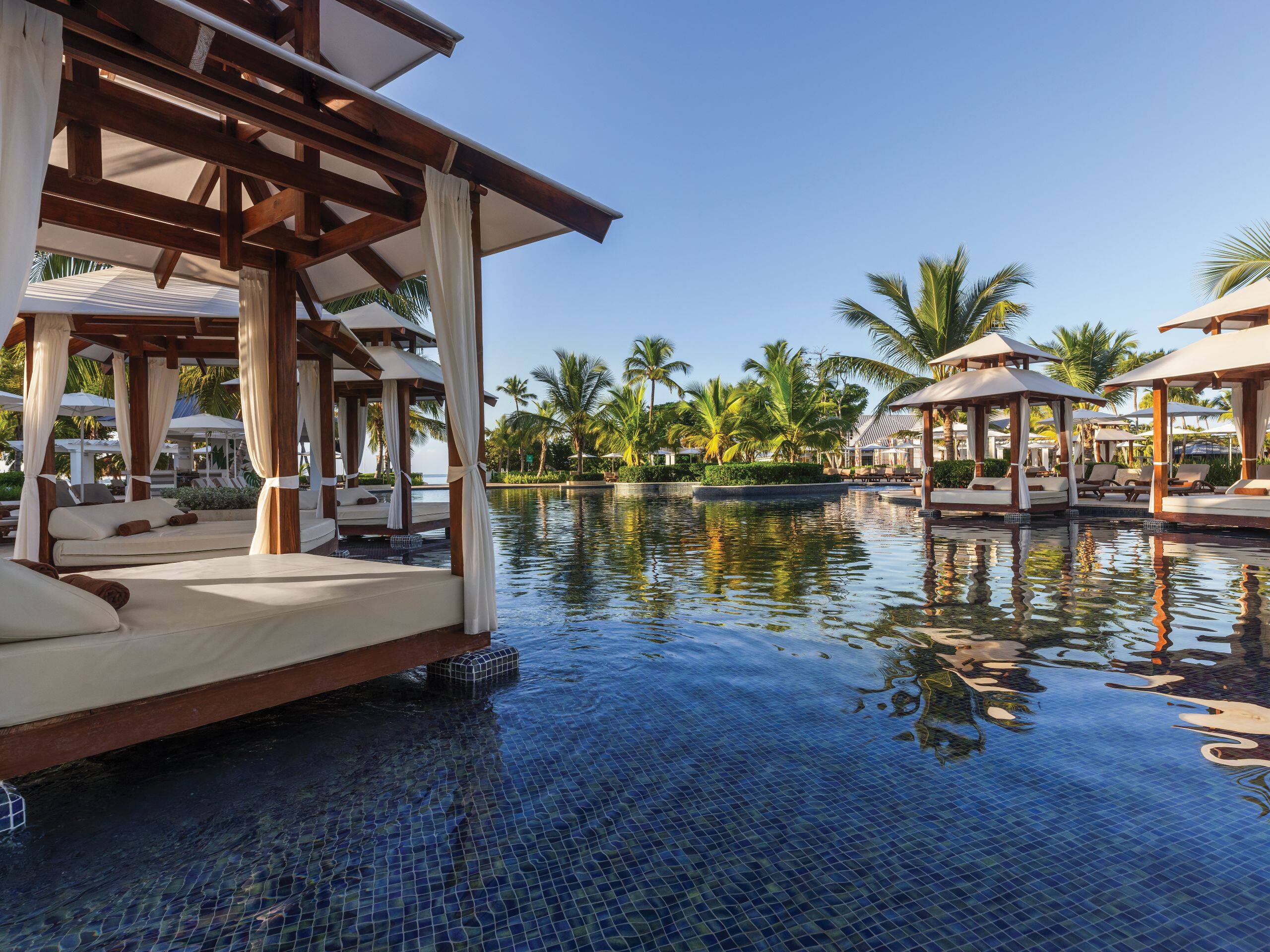 Dreams La Romana 3 Luxury poolside cabanas with palm trees reflection