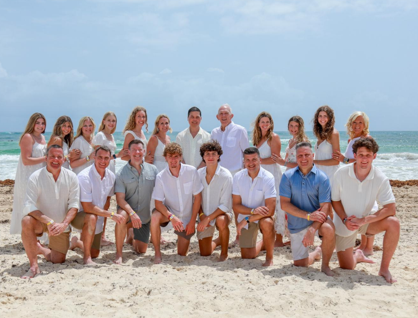 Group of people posing together on a beach.