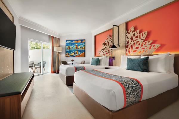 Modern hotel room with two beds and balcony view.