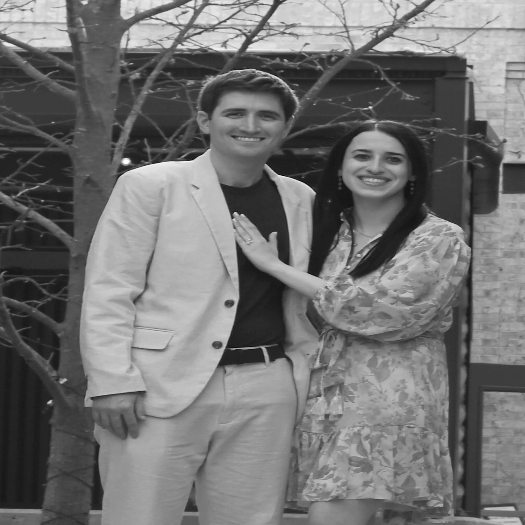 Smiling couple posing outdoors, black and white photo.
