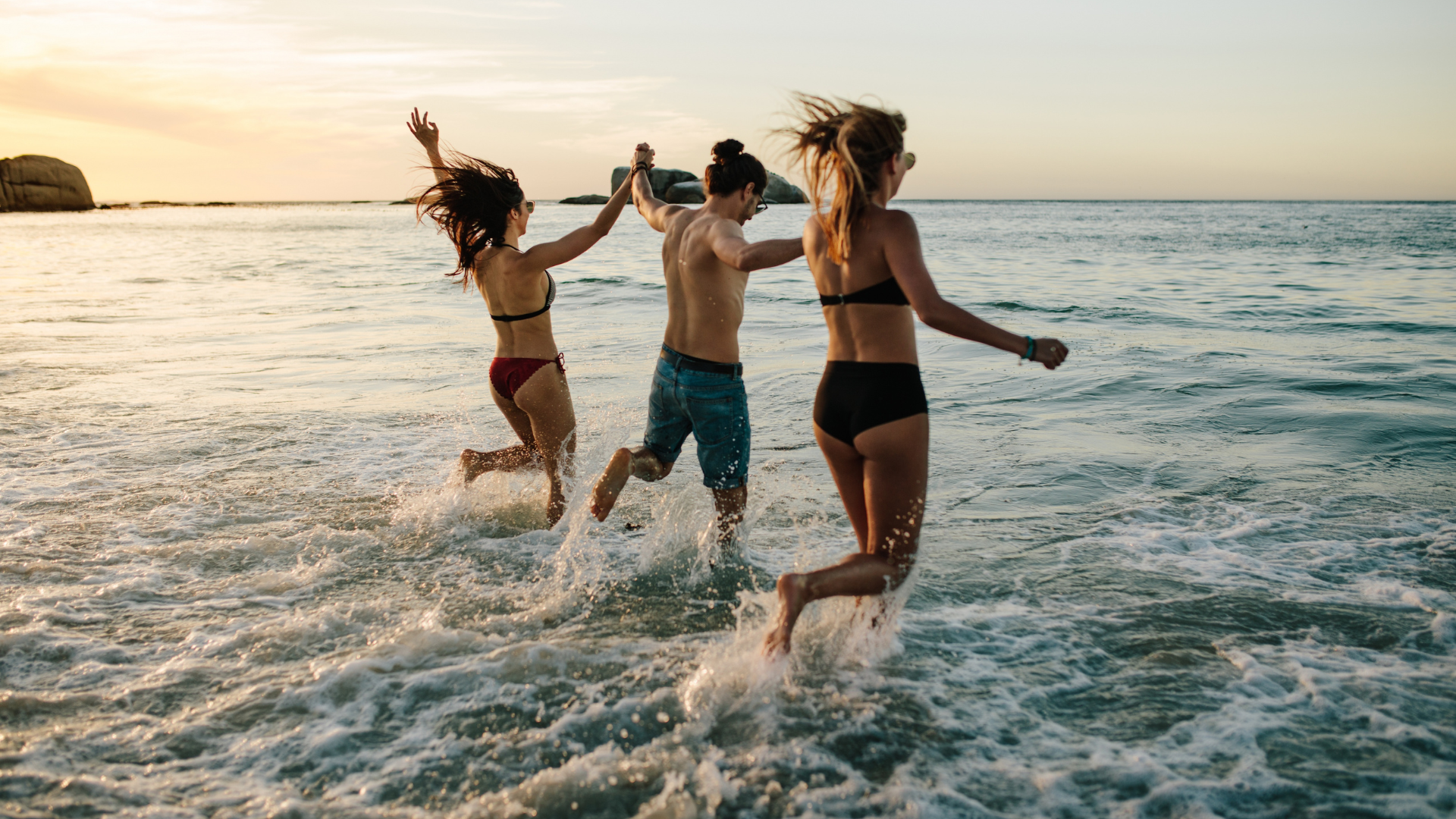 4 Friends running happily on a sunny beach