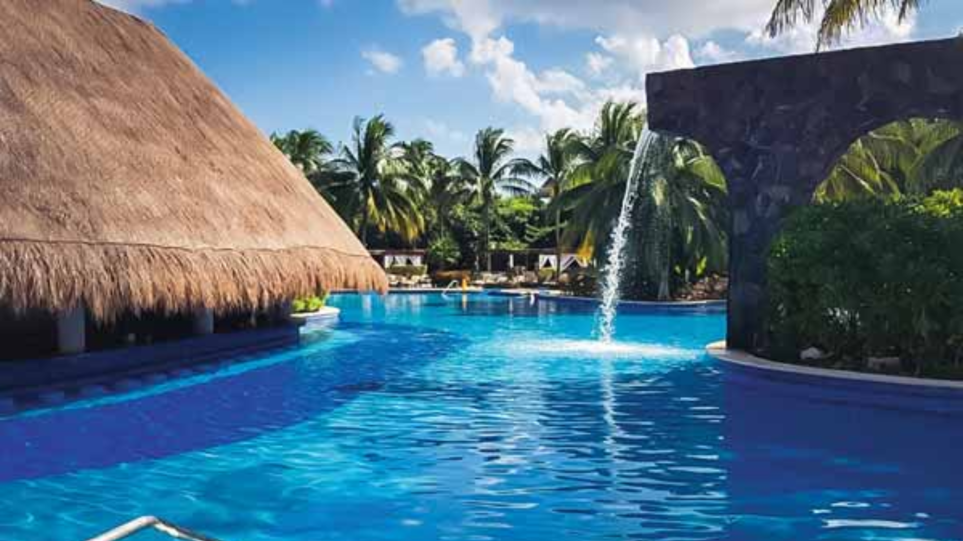9 Tropical resort pool with waterfall and palm trees.