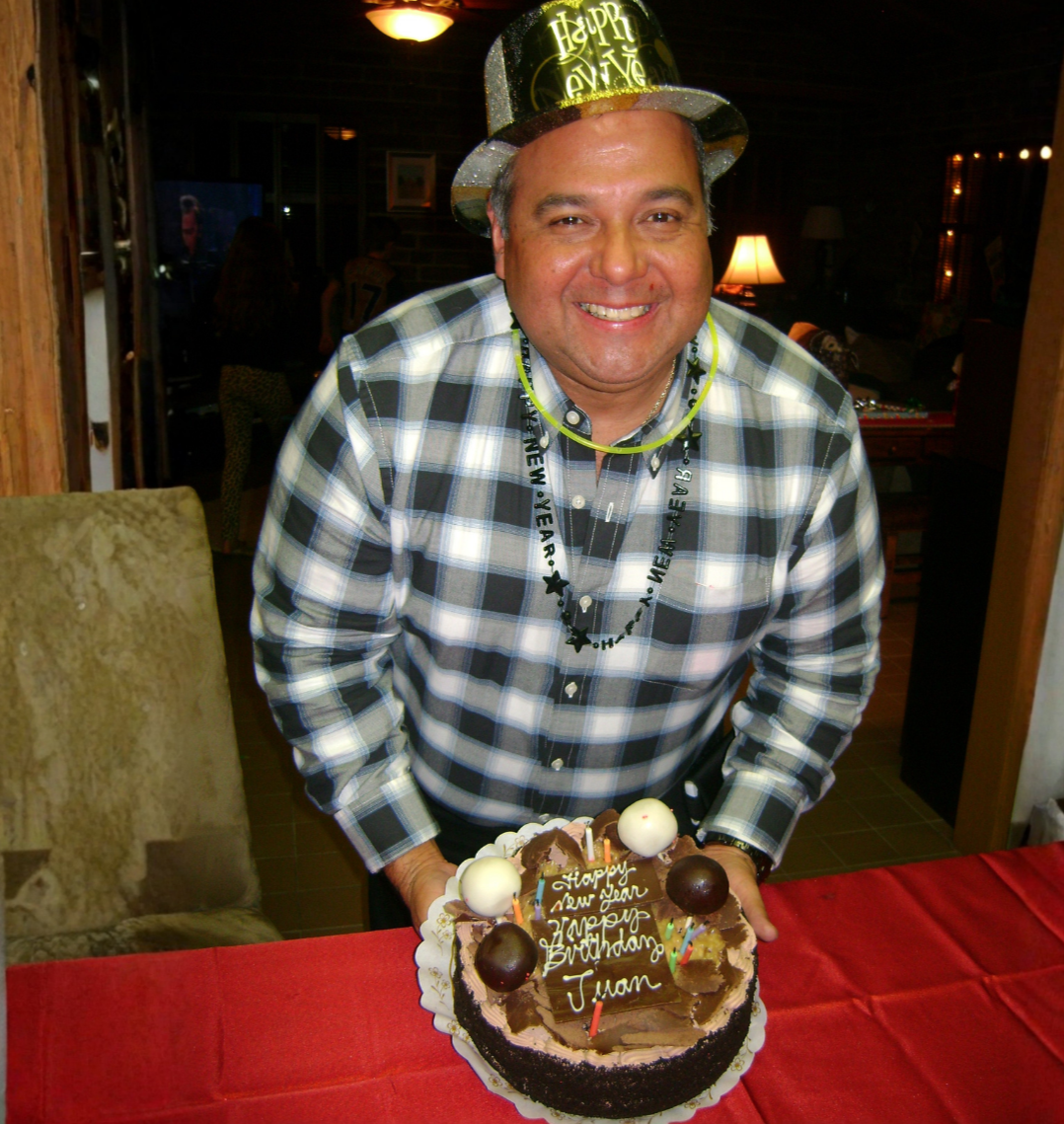 Smiling man with birthday cake and New Year hat.