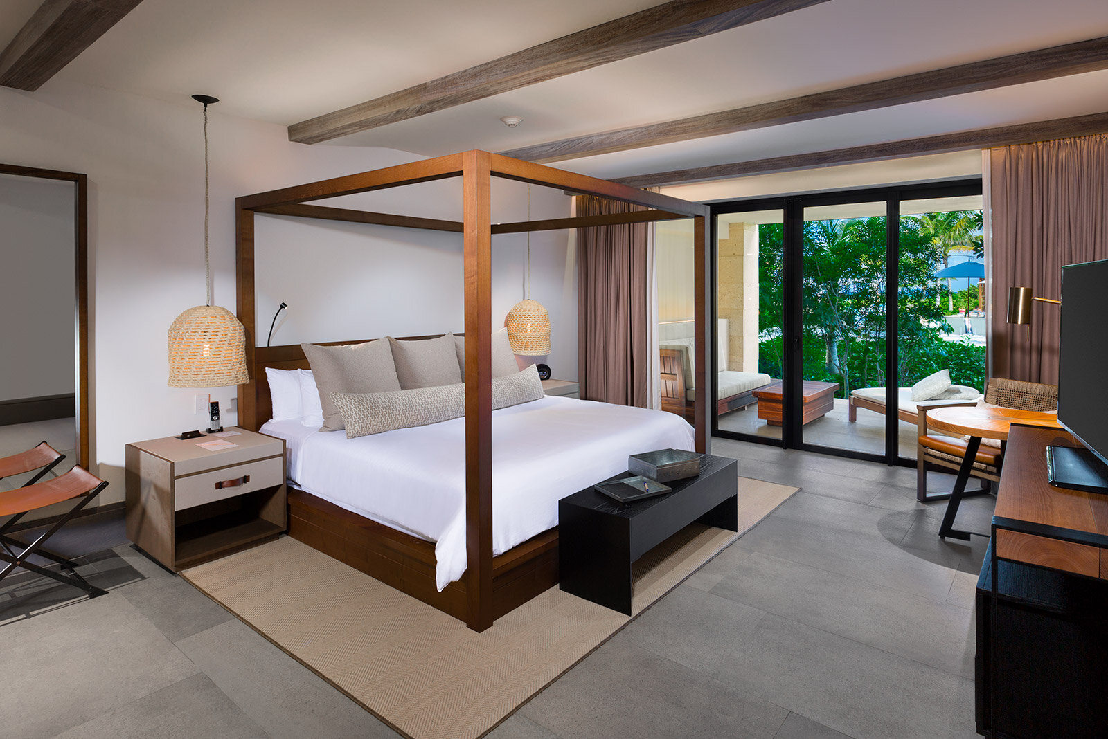 Modern hotel room with canopy bed and patio view.