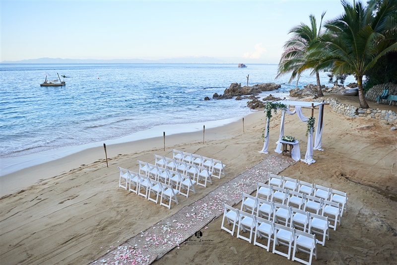 Beachfront wedding setup with chairs and canopy.