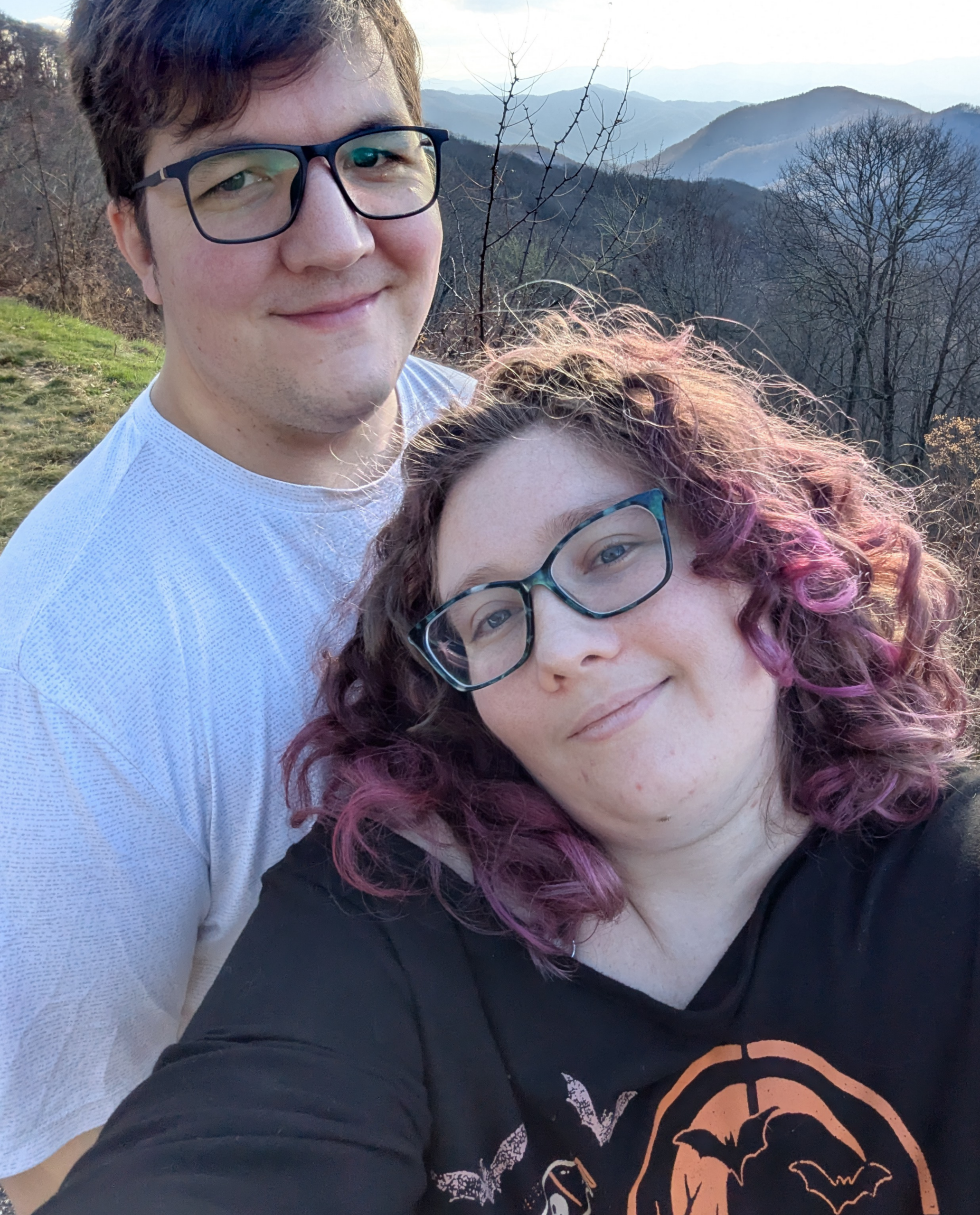 Couple posing at scenic mountain overlook.