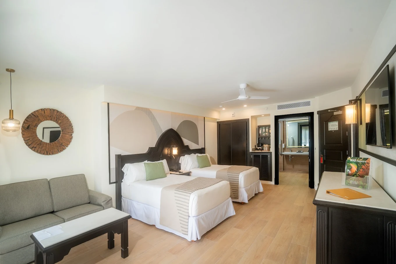 Modern hotel room with two beds and sofa.