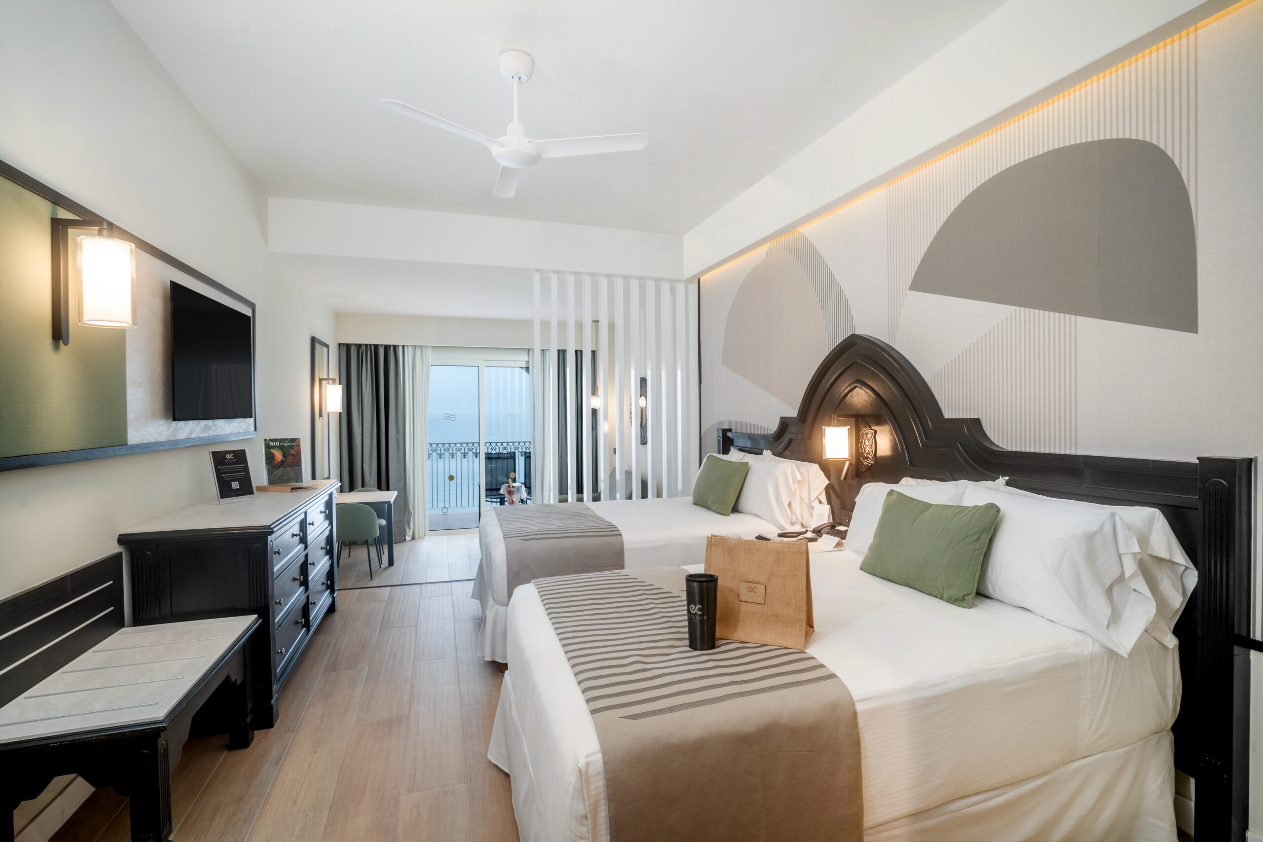 Modern hotel room with two beds and balcony.