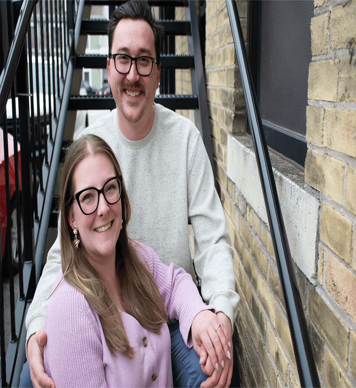 Smiling couple sitting on outdoor steps.