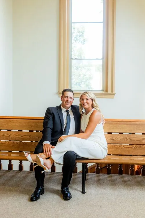 Kassidy and Nelius on a wooden bench by a tall window