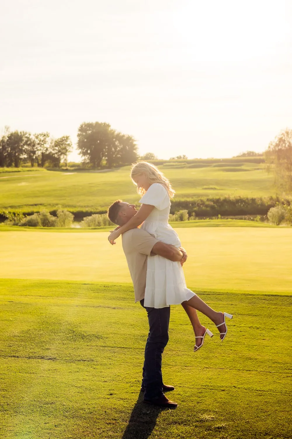 Nelius lifting Kassidy on an open lawn at golden hour