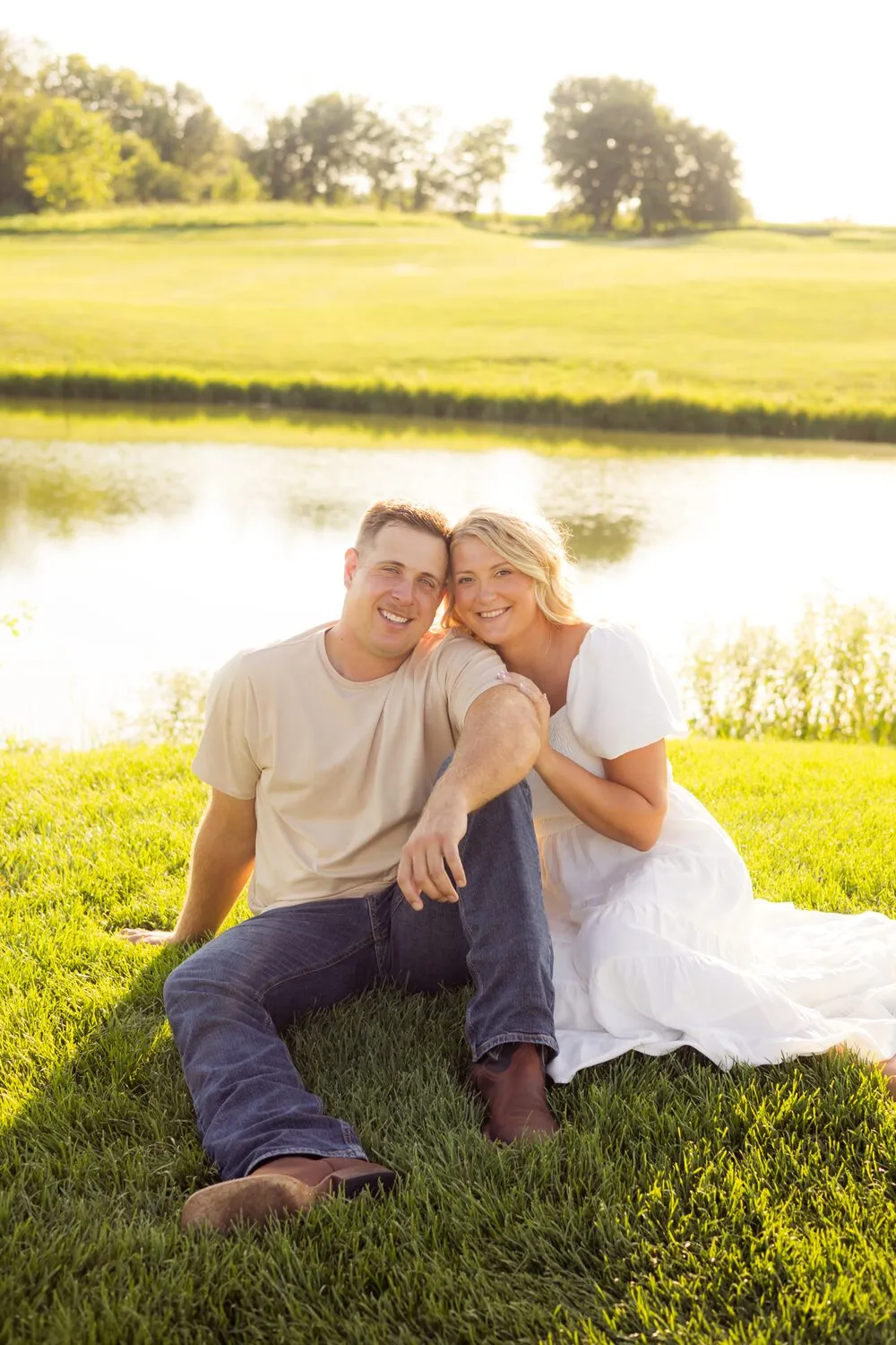 Kassidy and Nelius sitting on the grass beside a pond