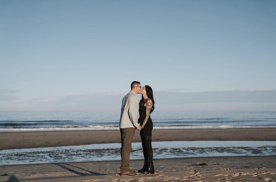 Sonya and Tyler sharing a kiss on the beach at sunset
